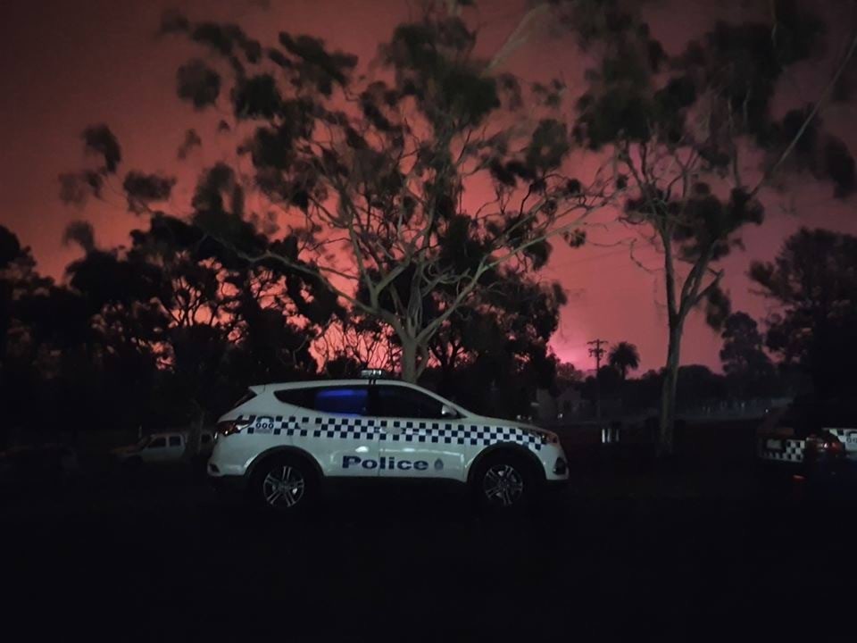 police vehicle in front of bushfire at night