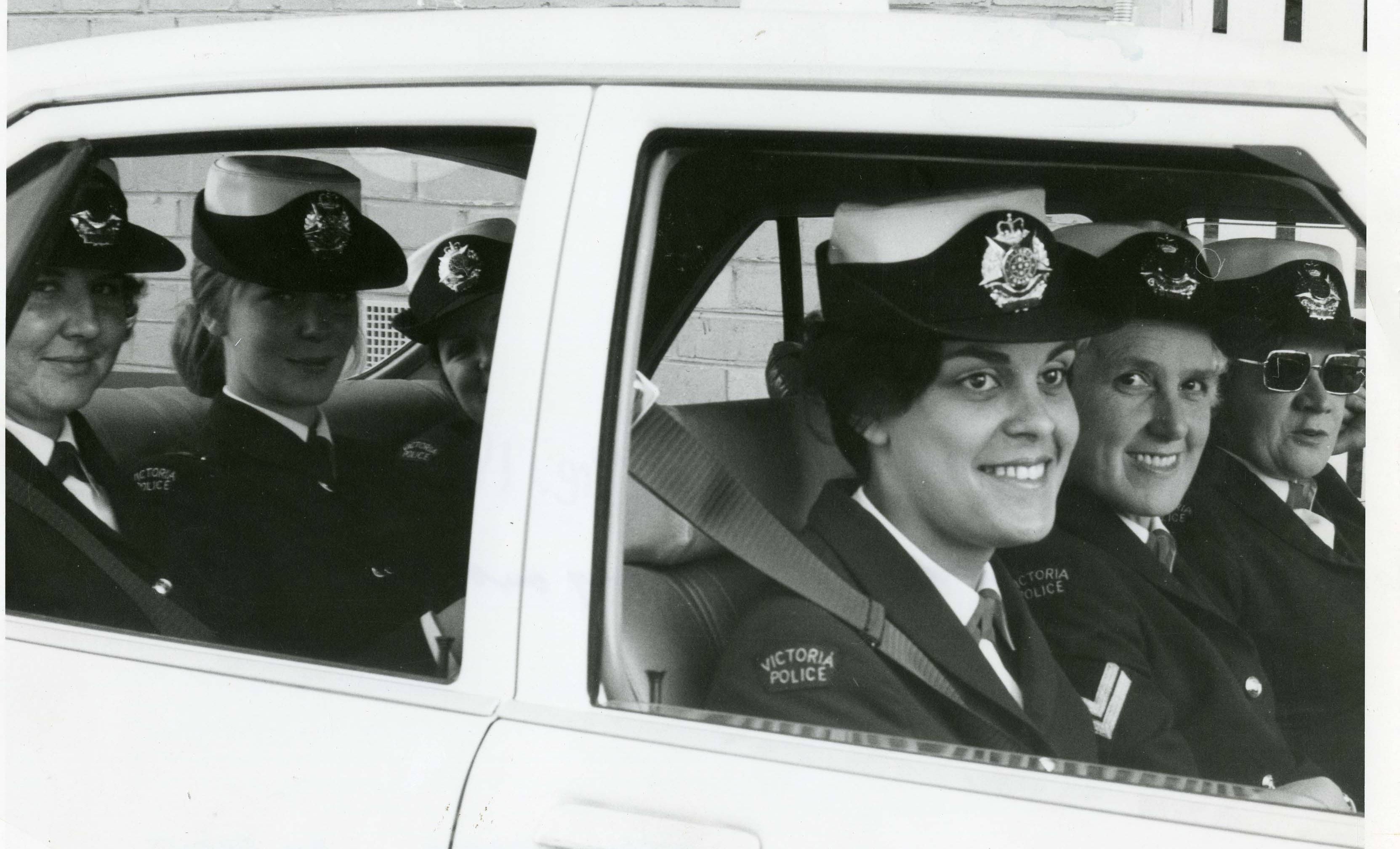 Female police officers wearing police uniform, inside a police vehicle. 