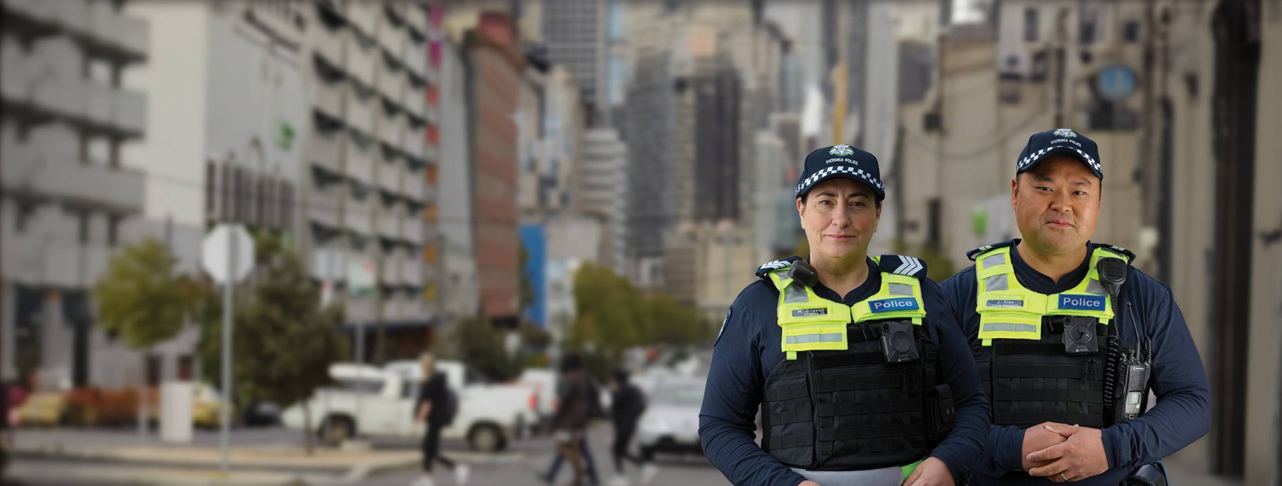 A female and a male uniformed Victoria police officers with a blurred city background