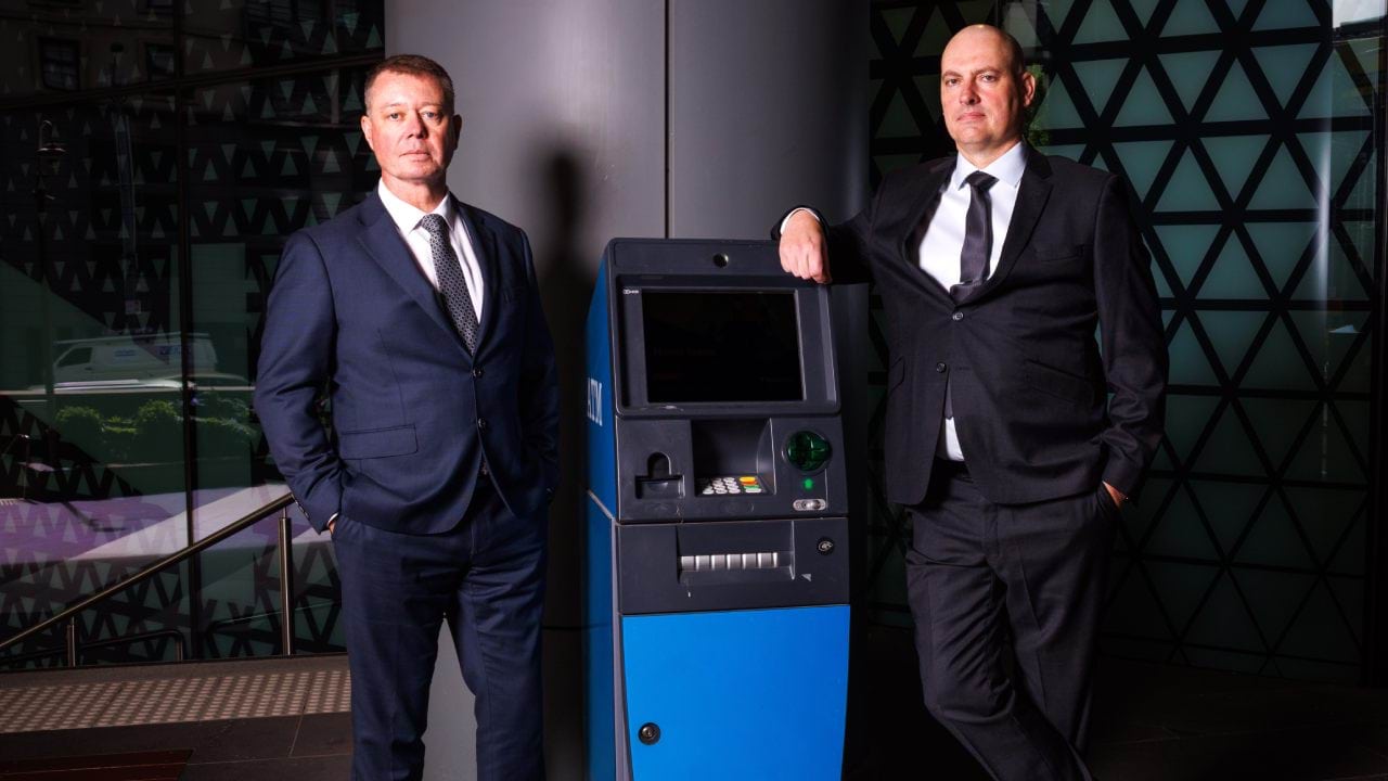 Cleaning up a money laundering syndicate - Two detectives standing next to an ATM