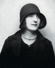 Madge Connor wearing a formal hat and outfit, with a pearl necklace. 